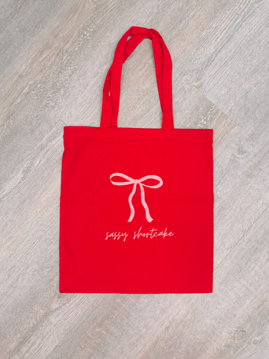 Red cotton Bow Tote Bag with pink bow design and "sassy shortcake" text.
