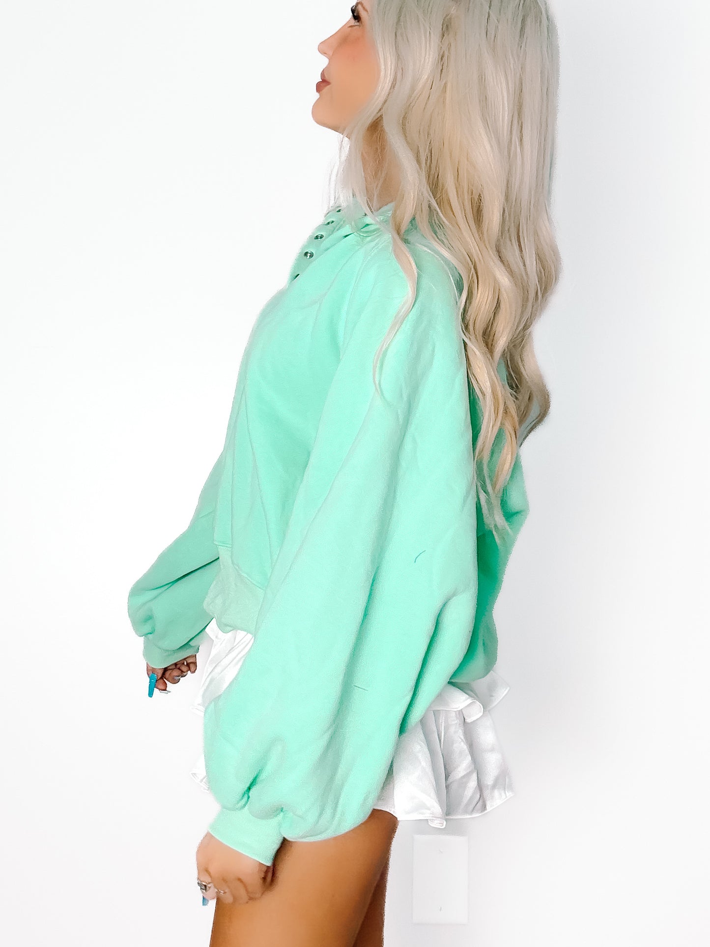 Seafoam green pullover, relaxed fit, styled with white ruffled shorts against a white backdrop.
