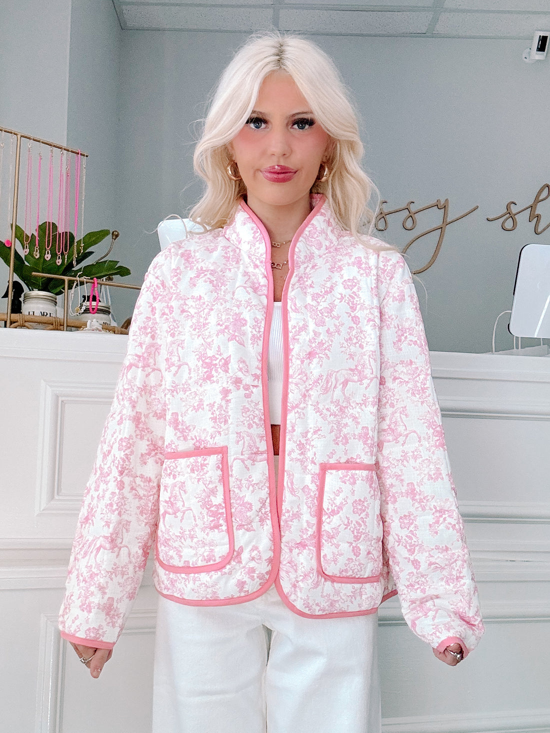 Person wearing a pink floral jacket in an indoor setting of a shopping boutique