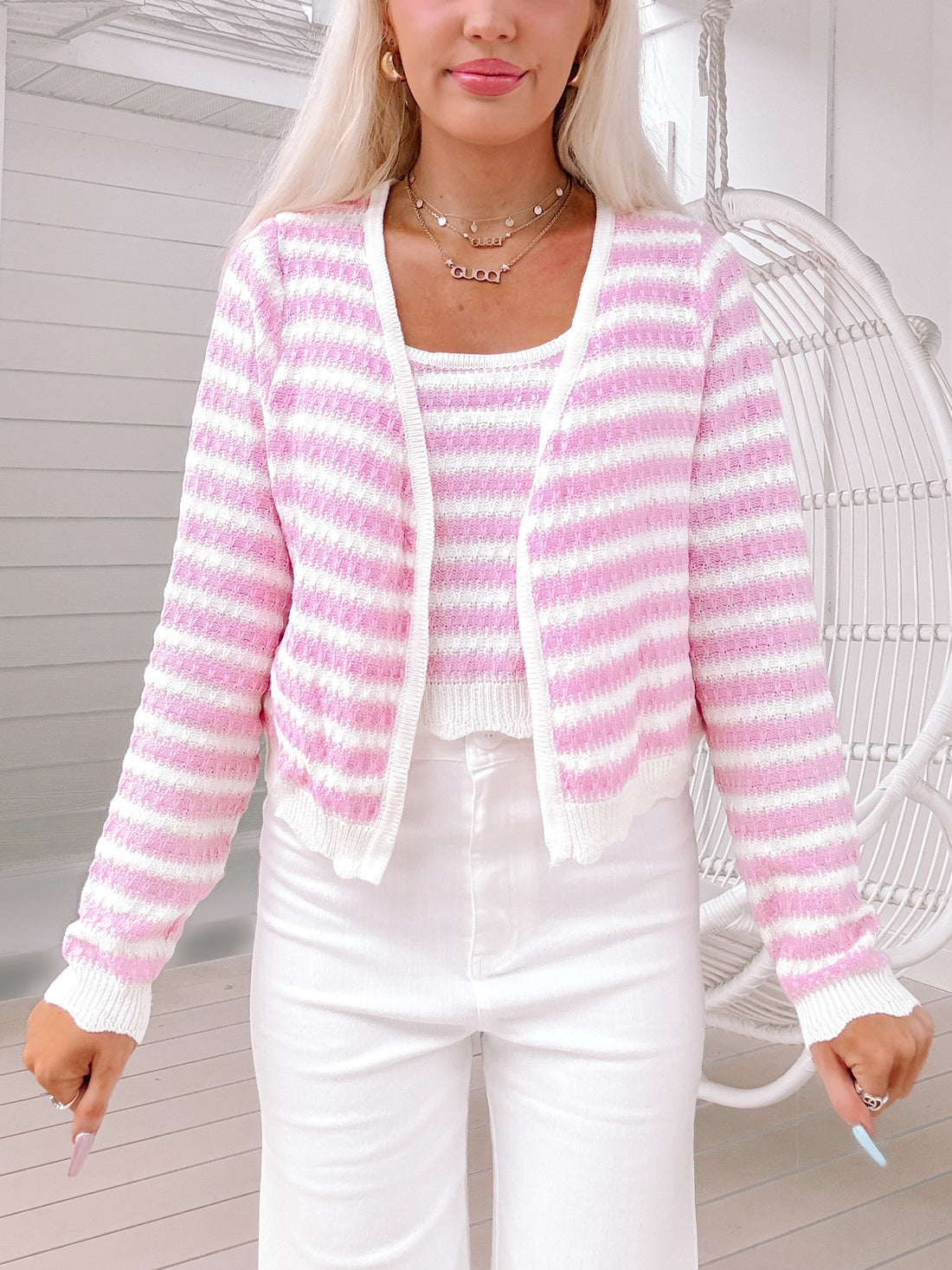 Pink and white striped knit sweater set, worn with white pants outdoors.
