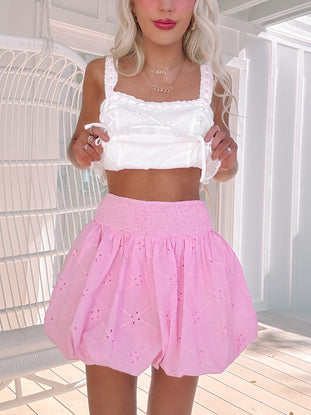 Close-up of eyelet texture and smocking on pink mini skirt