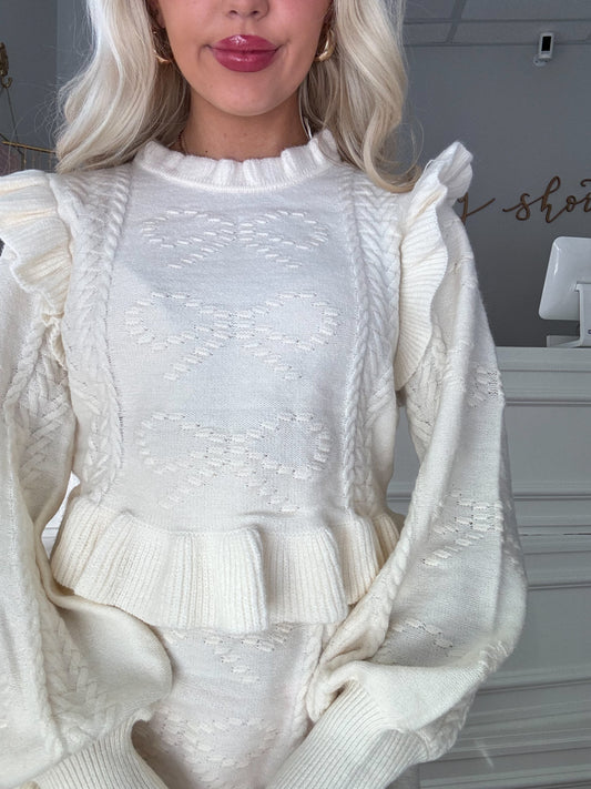 Cream-colored cable knit sweater set with ruffled detailing; close-up view.