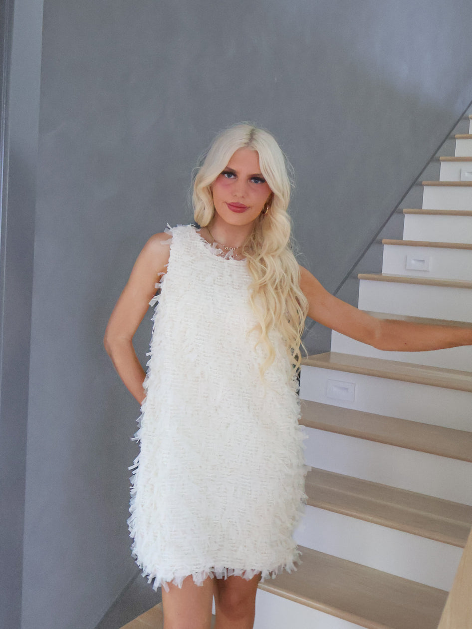 Model wearing Sassy Shortcake Snowfall Dress, white textured mini dress with statement bow back and flattering fitted shape.