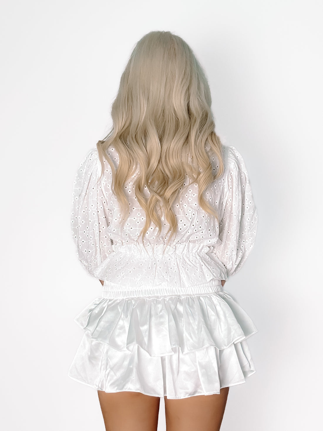 White eyelet top and satin mini skirt; rear view on model.
