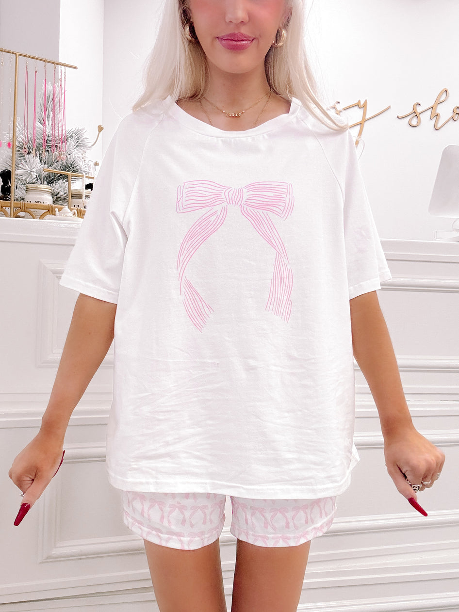 White lounge set featuring a pink bow graphic tee and coordinating shorts.
