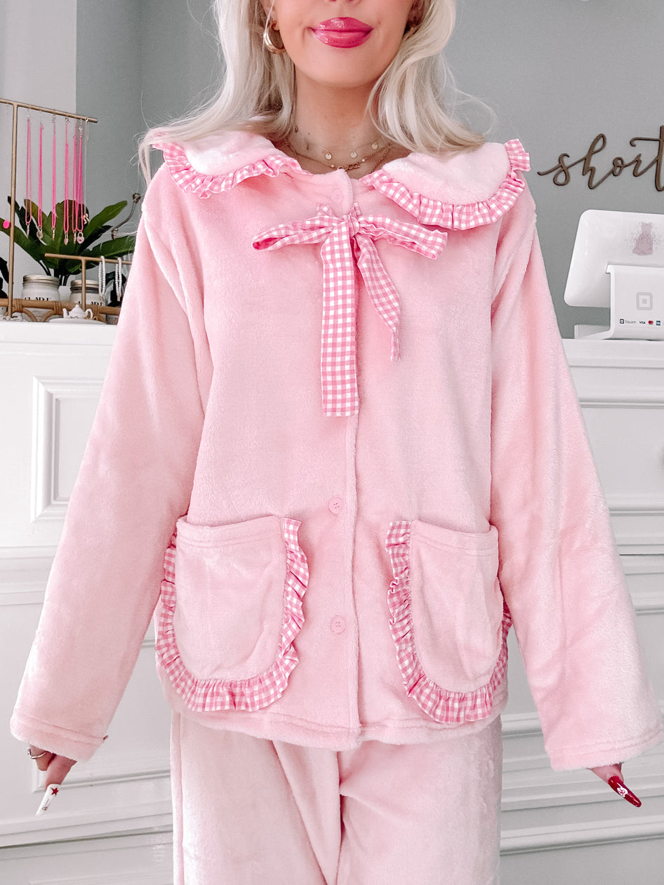 Pink plush pajama set with gingham trim and ruffled details.
