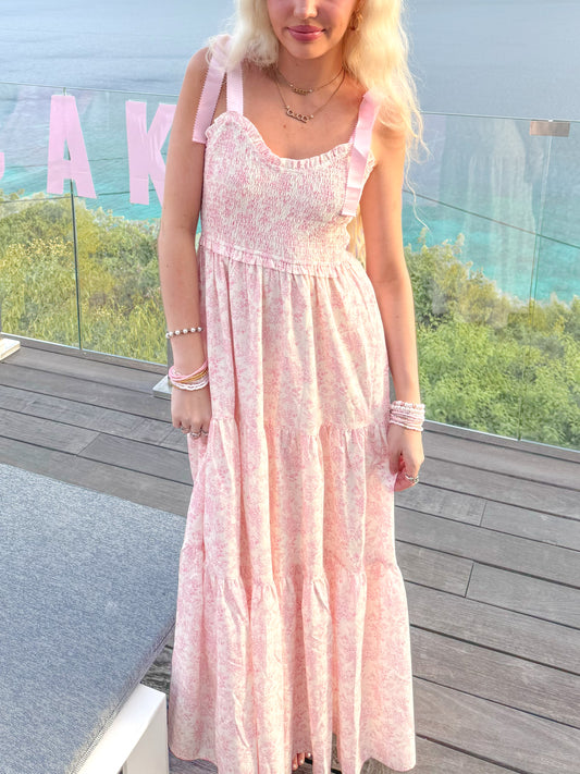 Close-up of Sassy Shortcake Sweet Pea pink floral maxi dress showing smocked bodice and bow tie straps, feminine summer style.
