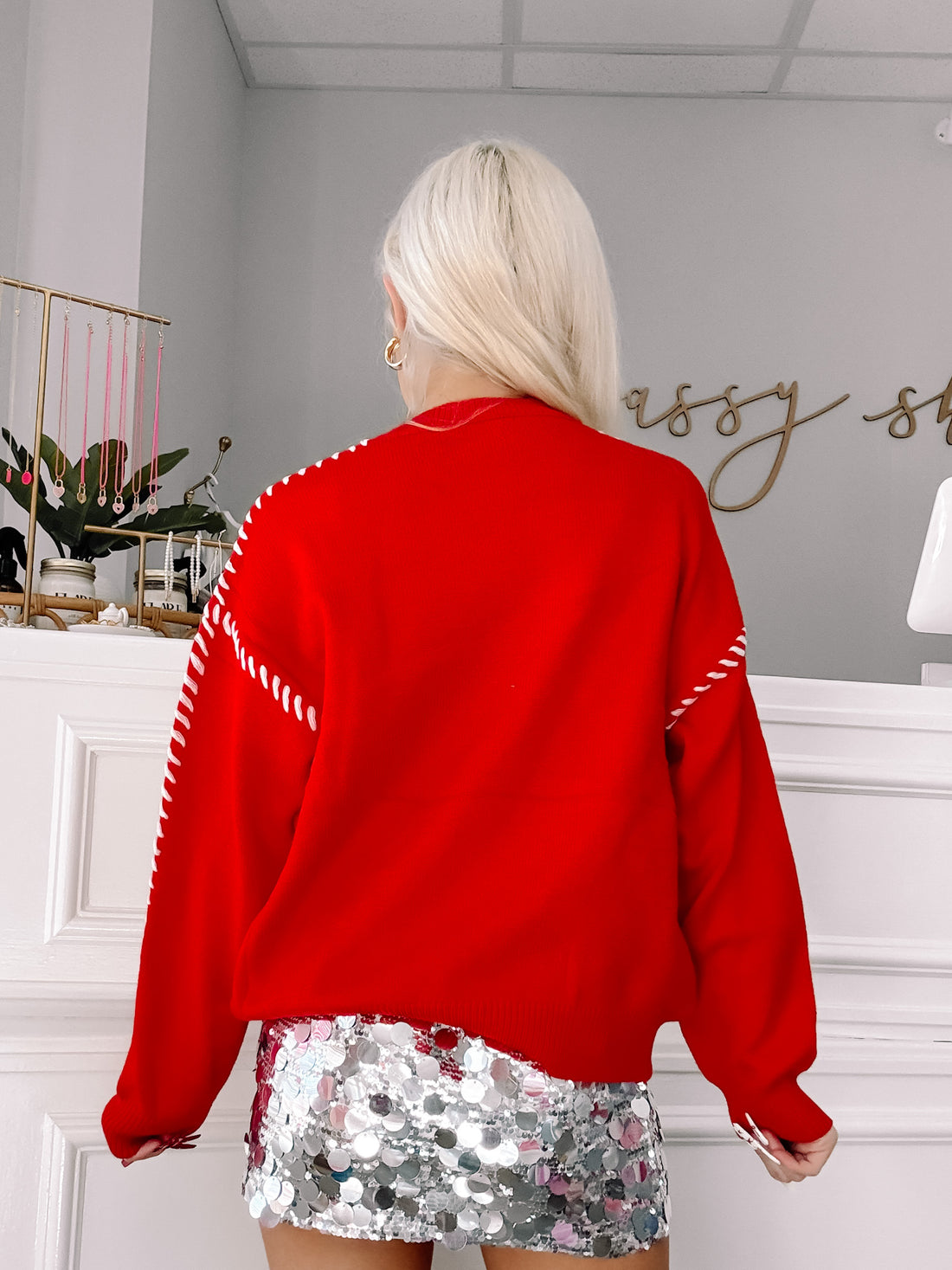 Red sweater with white stitching detail, shown from the back.
