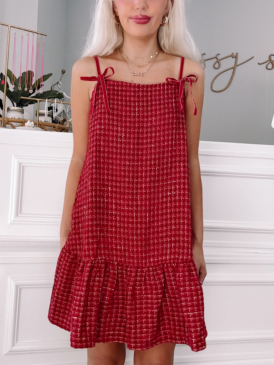 Red tweed mini dress with velvet straps and a tiered hem, shown on a model.
