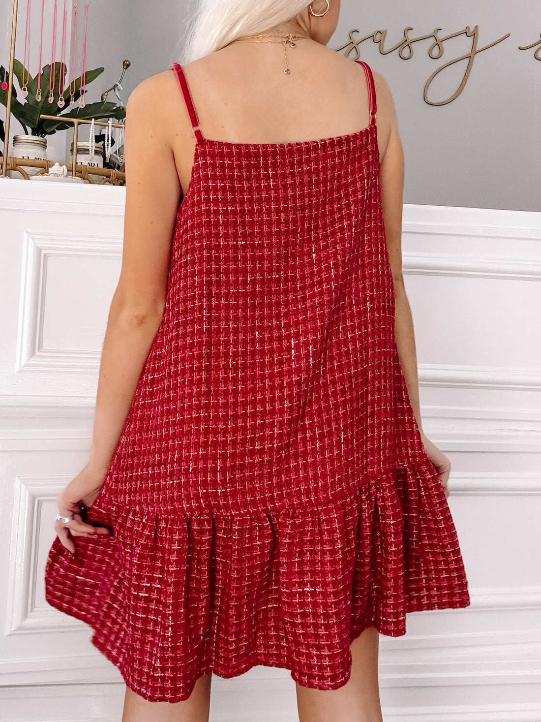 Red tweed mini dress with a ruffled hem, shown from the back against a white wall.
