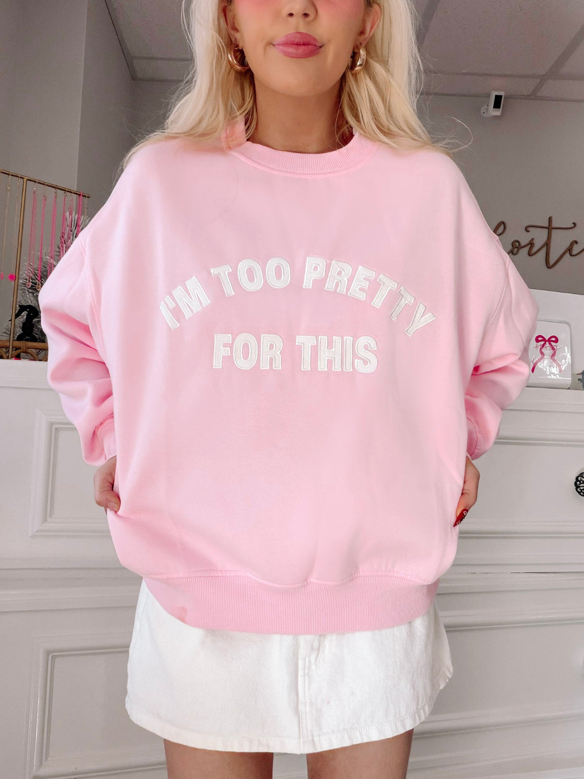 I'm Too Pretty For This Pink Crewneck from Sassy Shortcake - Person wearing a pink sweatshirt with text in a room.