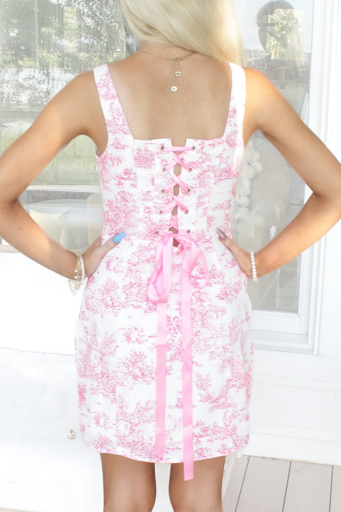 Pink toile print dress with a corset-style back and pink ribbon lacing.
