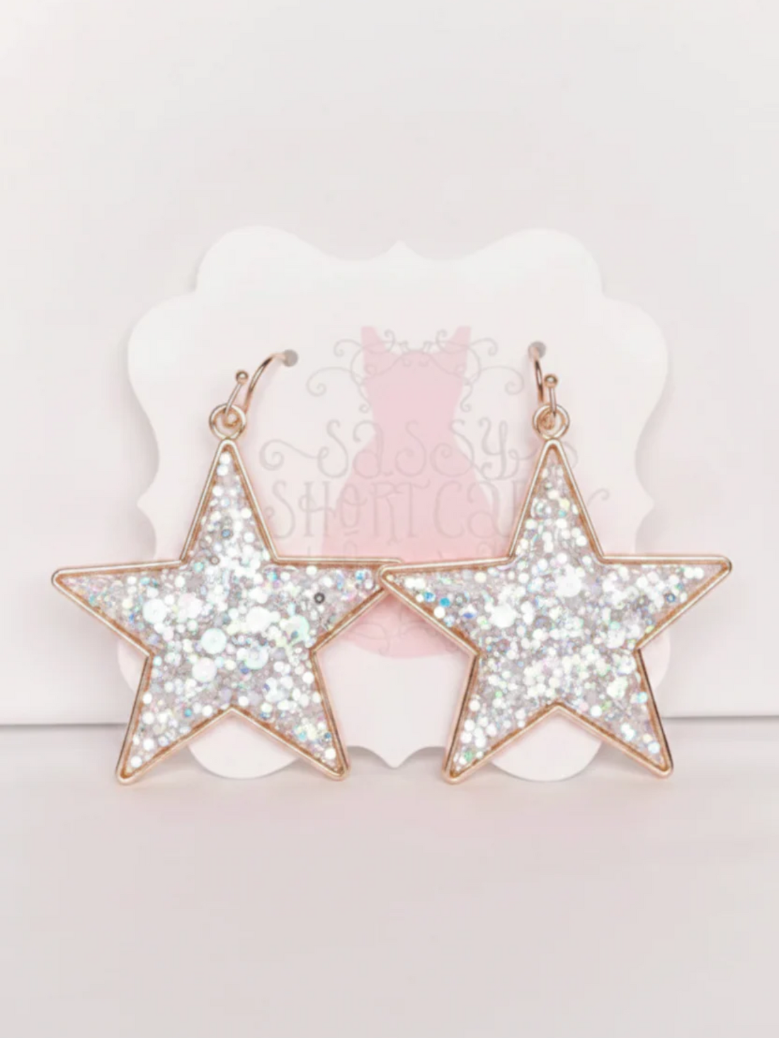 White Chasing Stars Earrings from Sassy Shortcake, featuring white glitter star earrings with gold hoops for a cute sparkly finish.