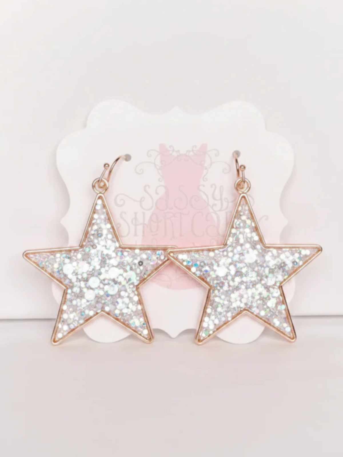 White Chasing Stars Earrings from Sassy Shortcake, featuring white glitter star earrings with gold hoops for a cute sparkly finish.