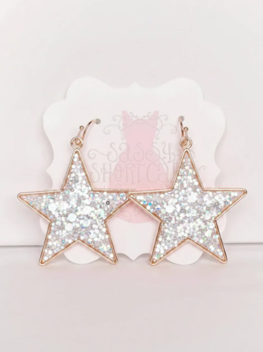 White Chasing Stars Earrings from Sassy Shortcake, featuring white glitter star earrings with gold hoops for a cute sparkly finish.