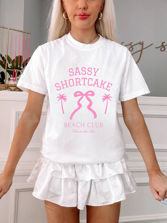 Model front-facing in white bow tee, bright pink graphic pops against white backdrop.