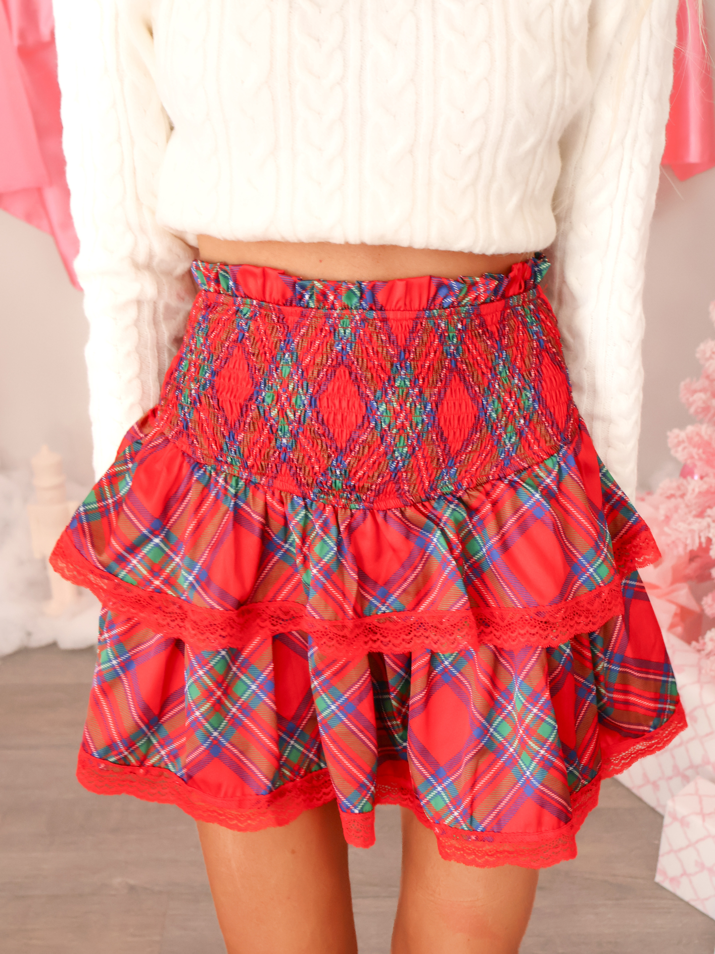 Close-up of Sassy Shortcake Winter Wishes Skirt showing smocked waist, red tartan pattern, tiered ruffles, and delicate lace hem