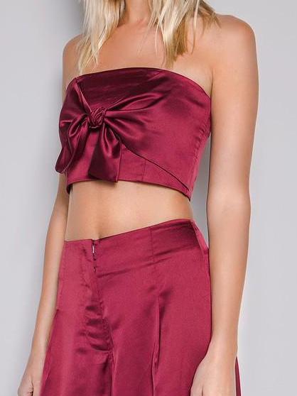 Burgundy satin crop top with a bow detail, paired with matching high-waisted pants.
