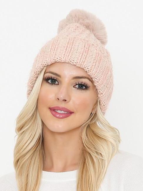 Pink knit beanie with fluffy pompom, worn by blonde woman.
