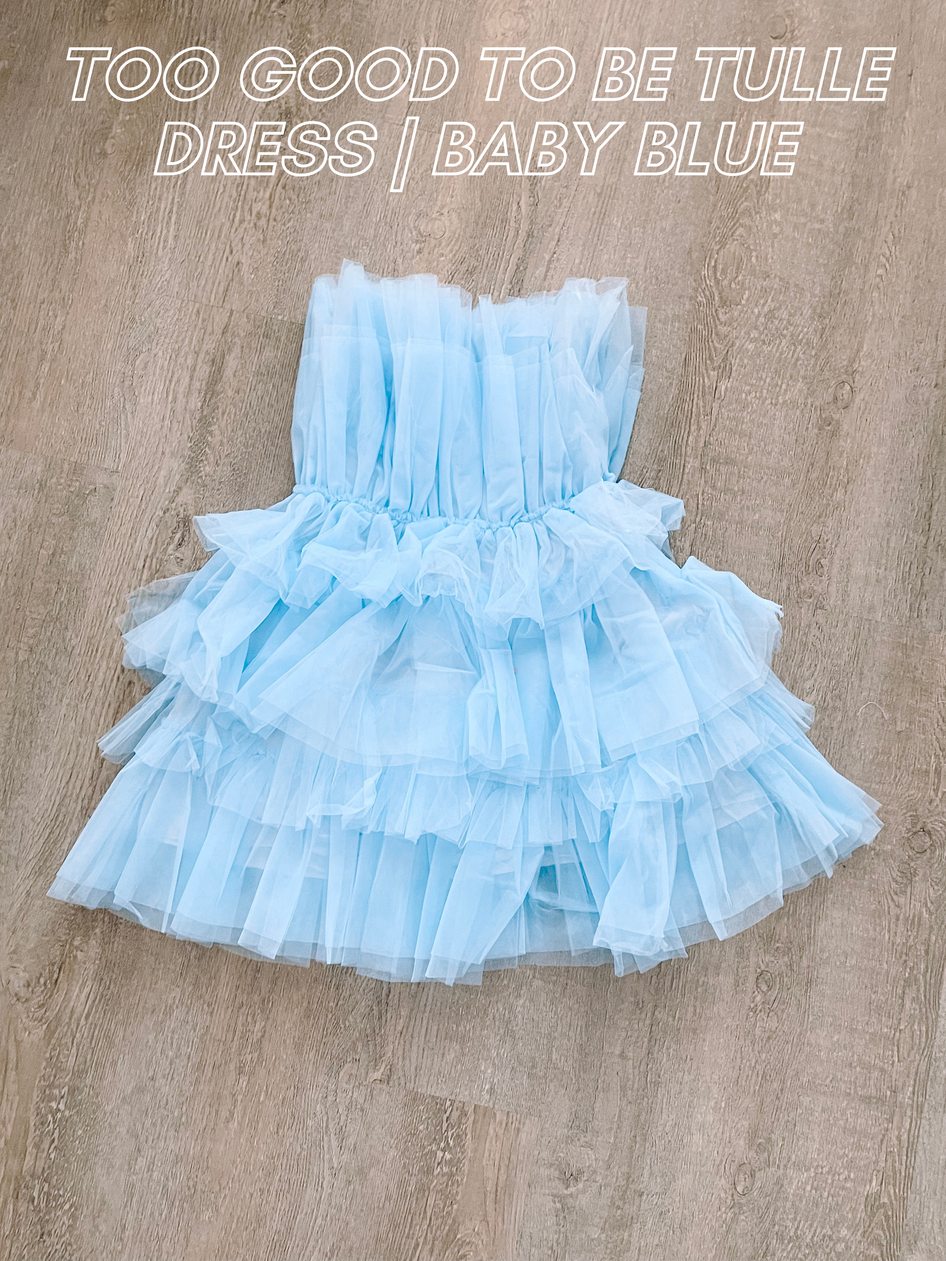 Light blue tulle dress, layered ruffles, lying on wood background.
