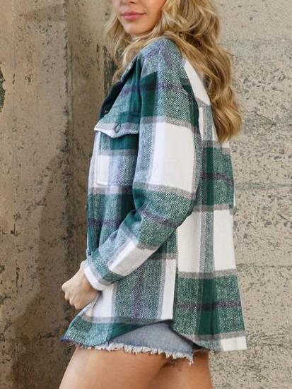 Green and white plaid shacket, long sleeves, worn against a stone wall.
