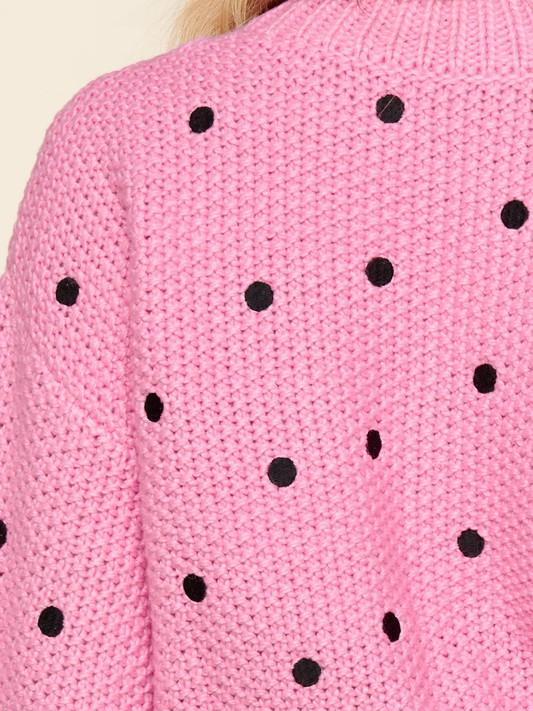 Pink knit sweater with black polka dots.

