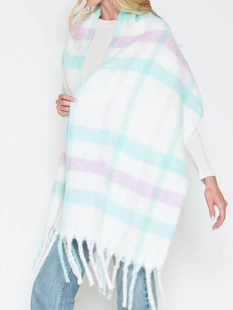 Fuzzy pastel plaid scarf with fringe detail, draped over model.
