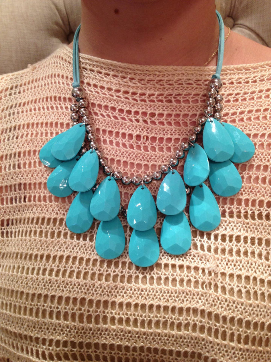 Teal teardrop necklace with silver beads on beige knit sweater
