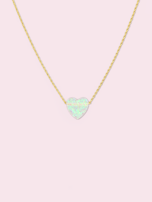 Dainty gold chain necklace featuring a pale opal heart pendant against a light pink backdrop. White Heart Crystal Necklace from Sassy Shortcake
