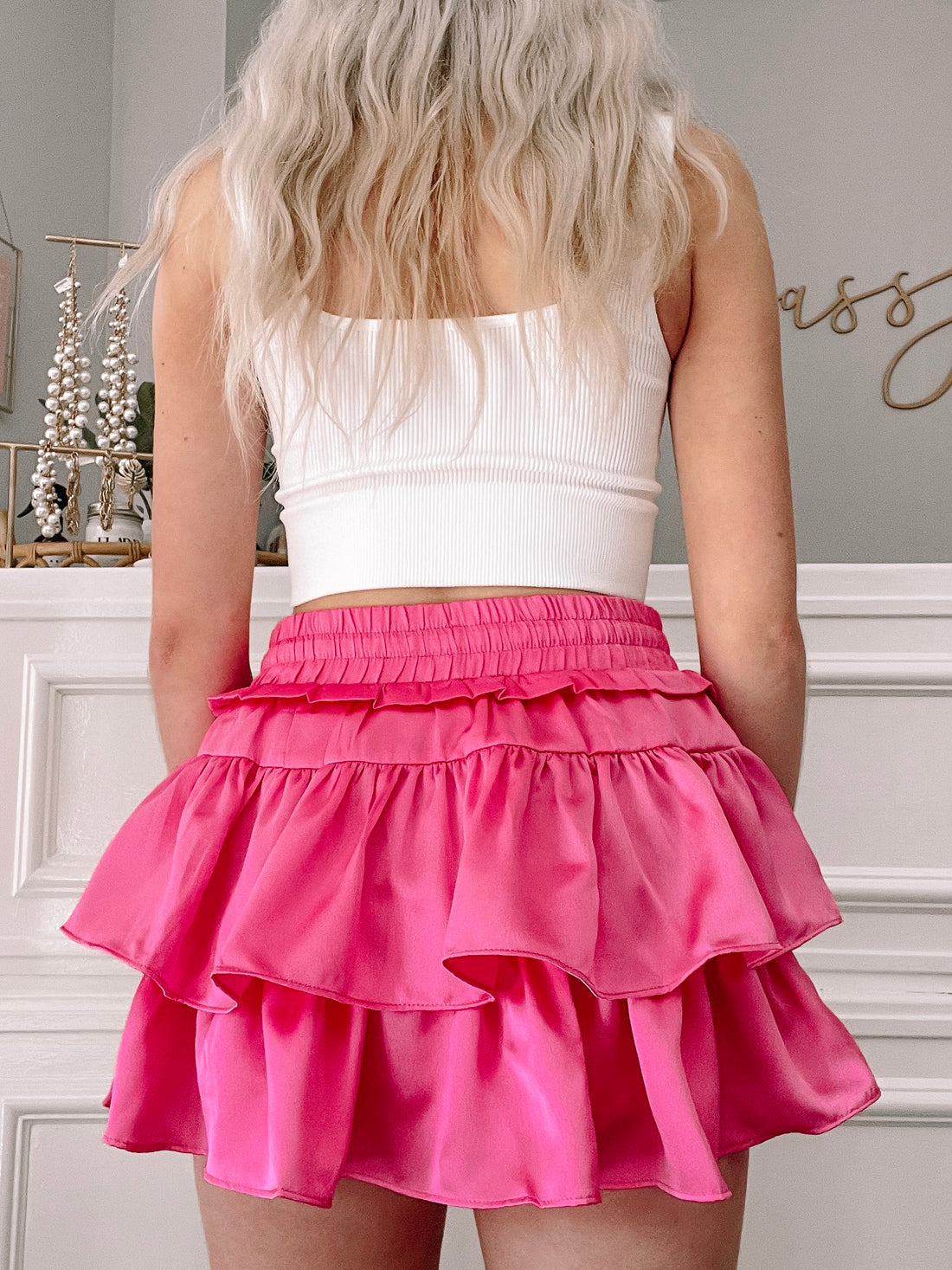 Hot pink satin mini skirt with double ruffle detailing, shown from the back.
