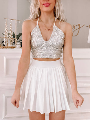 Silver sequined halter top and white pleated tennis skirt, styled for a festive occasion.
