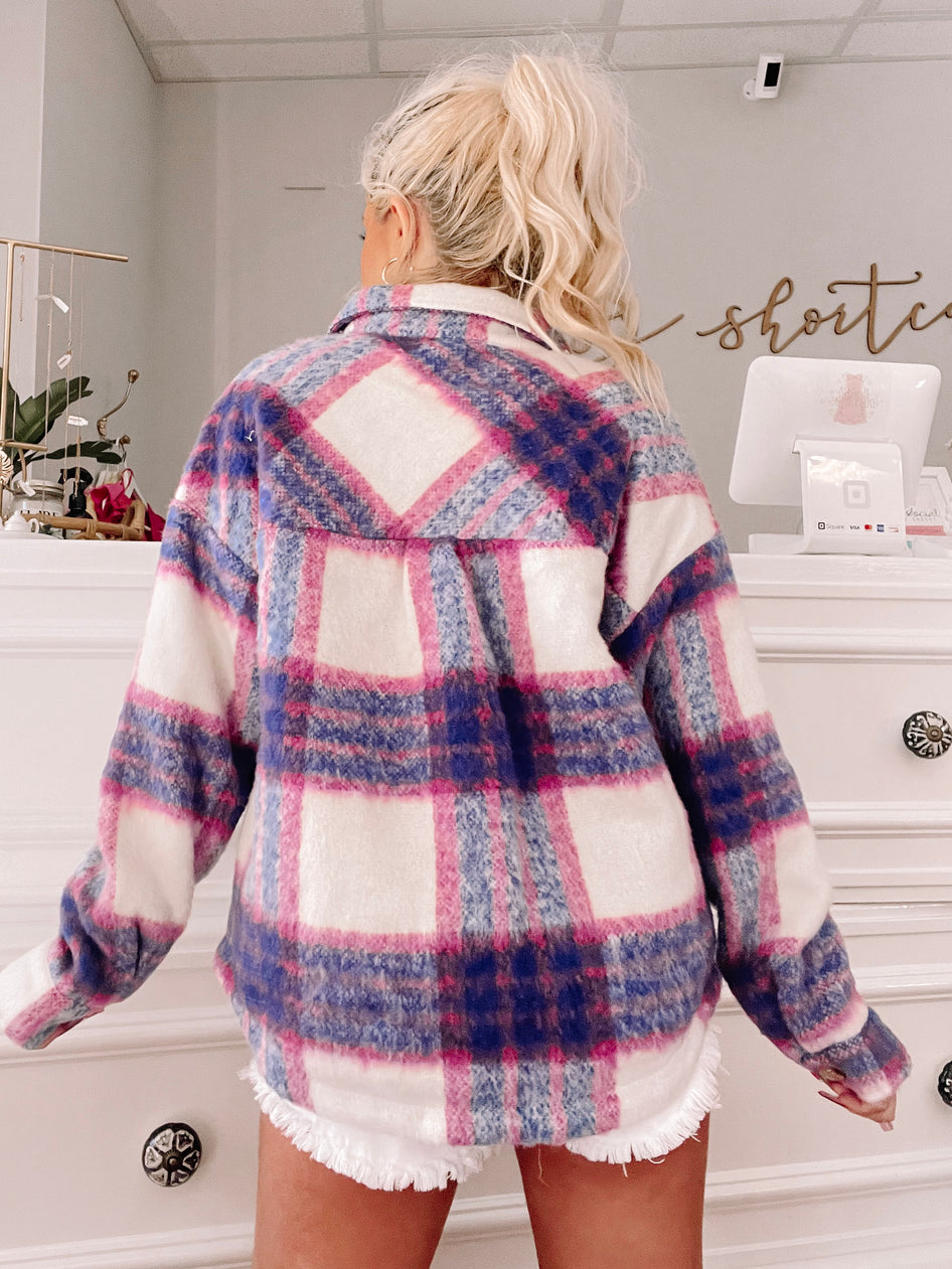 Cozy pink, purple, and white plaid shacket shown from the back in a shop setting.
