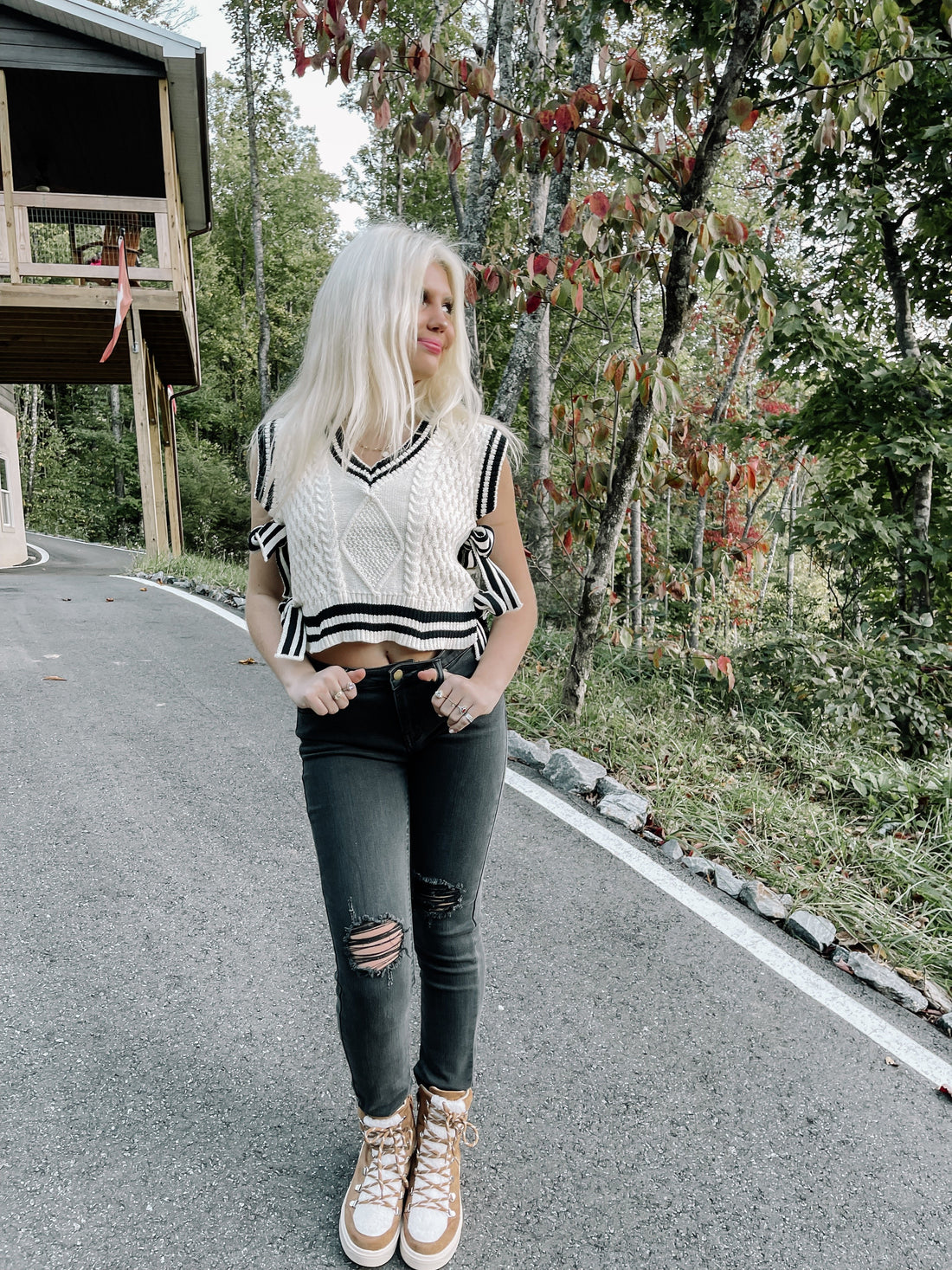 Woman in pink sweater vest outdoors on a path.
