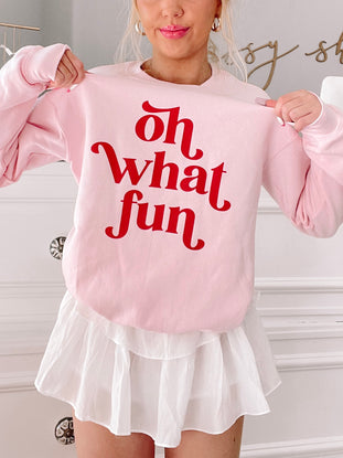 Pink crewneck sweatshirt with playful "Oh What Fun" text in red.
