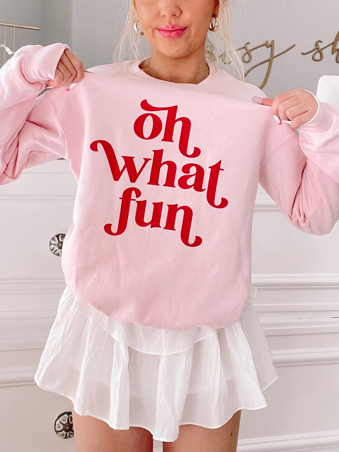 Pink crewneck sweatshirt with playful "Oh What Fun" text in red.
