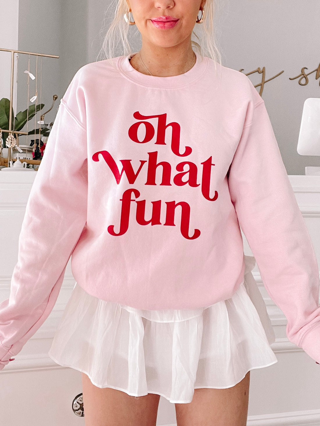 Pink "Oh What Fun" crewneck sweatshirt with red lettering.
