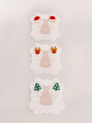 Miniature holiday-themed earrings; Santa hats, reindeer, and Christmas trees.
