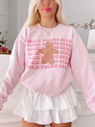 Pink Cookie Baking Crewneck sweatshirt featuring a gingerbread man graphic.
