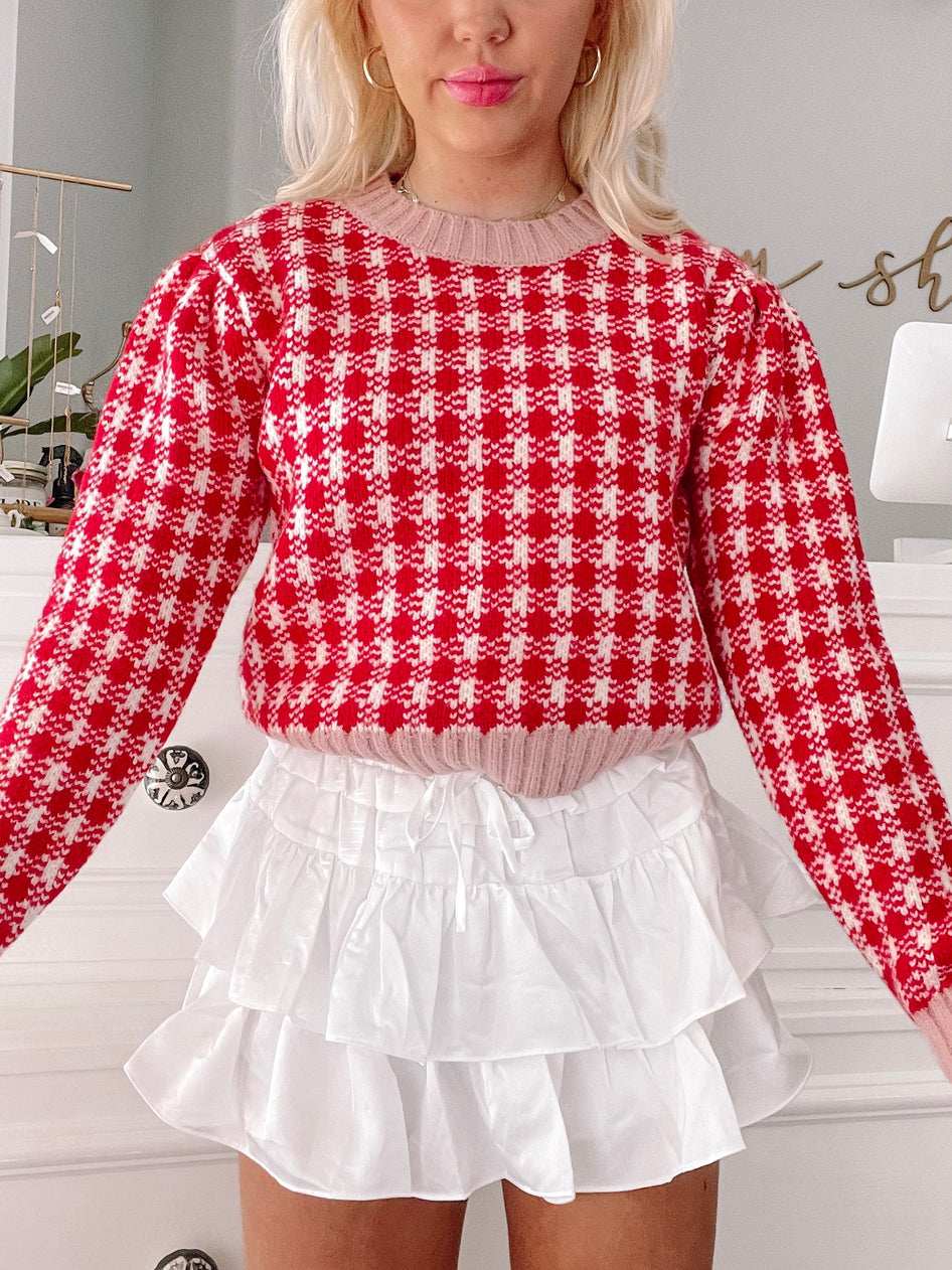 Red and white gingham knit sweater styled with a white tiered ruffle skirt.
