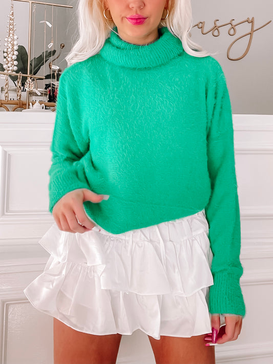Fuzzy emerald green turtleneck sweater paired with a white ruffled mini skirt.