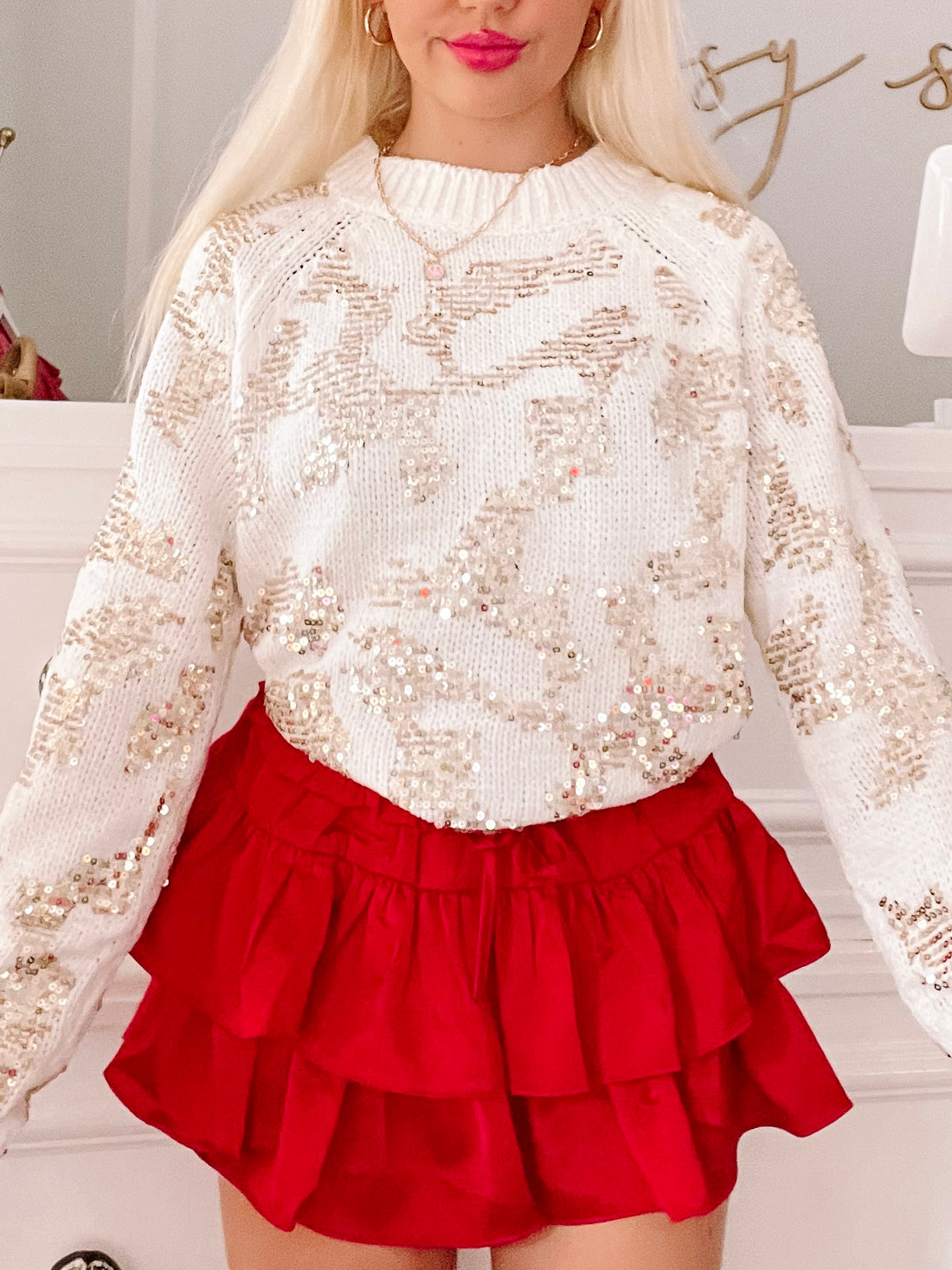Cream sequin-embellished sweater paired with a red layered mini skirt.
