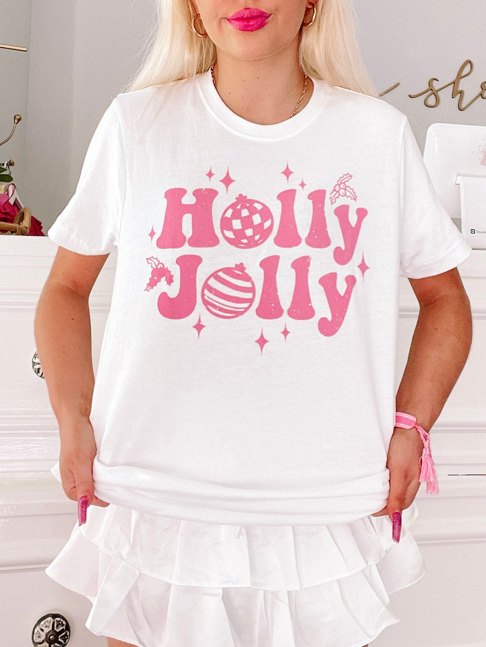 Pink "Holly Jolly" graphic tee on a model, festive holiday design.
