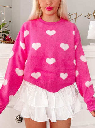 Fuzzy pink sweater adorned with white hearts, modeled over a white tiered skirt.
