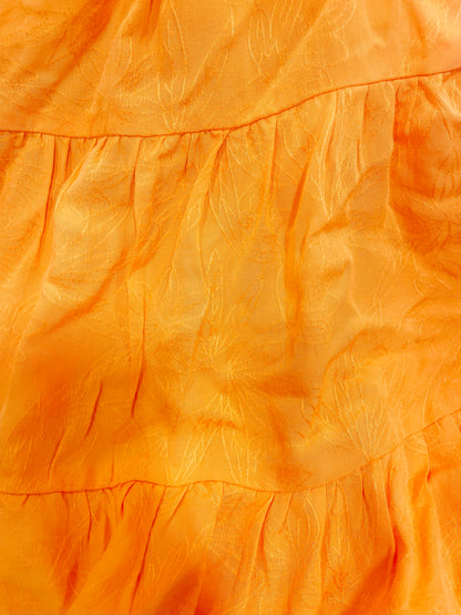 Close-up of tangerine dress fabric with subtle textured pattern.
