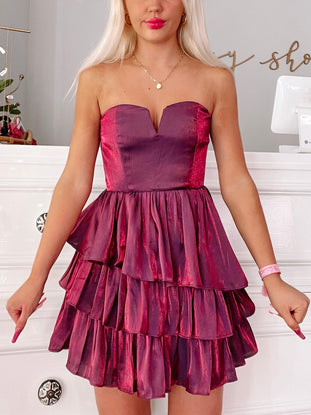 Burgundy tiered ruffle mini dress; strapless sweetheart neckline.
