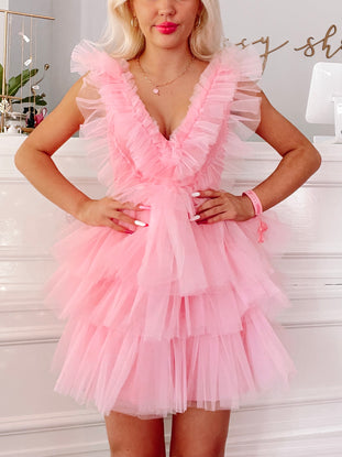 Pink tulle mini dress with layered ruffles, V-neck, and sleeveless design.
