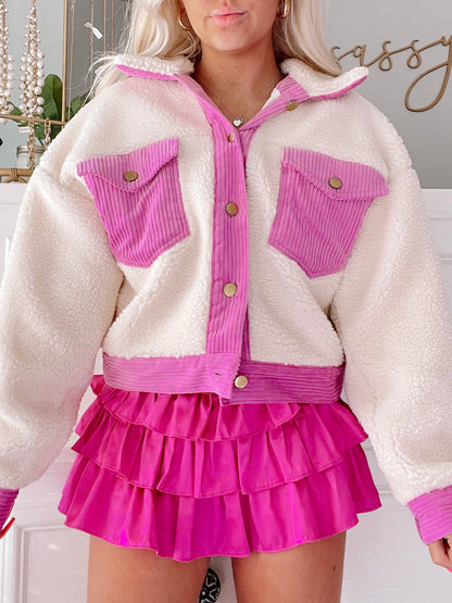 Cream sherpa jacket with pink corduroy accents, modeled with a fuchsia ruffle skirt.
