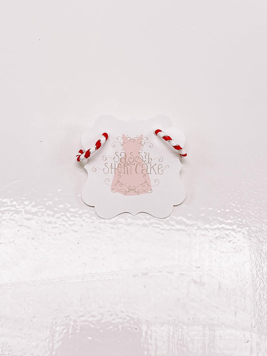 Candy cane-striped hoop earrings displayed on a product tag against a white background.