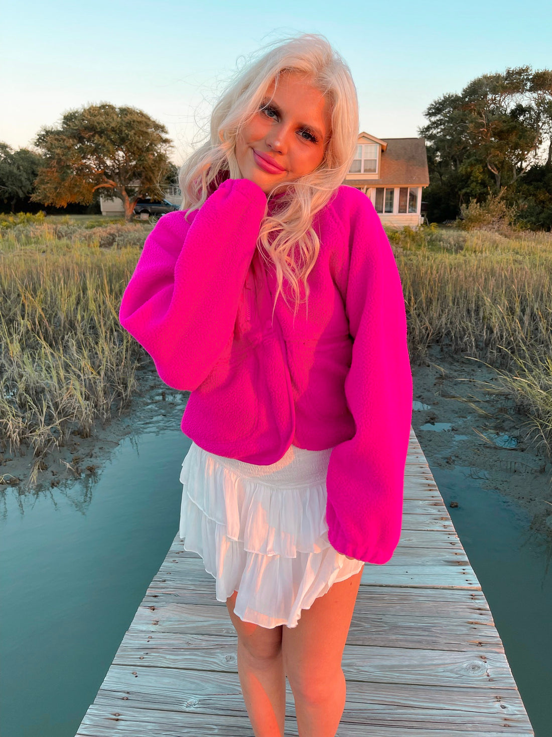 Fuchsia fleece jacket worn outdoors at sunset, near water.
