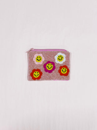 Pink beaded pouch with smiling flower accents.
